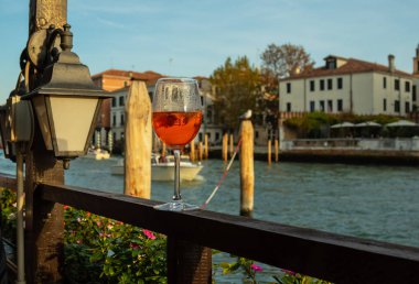  Venedik arka planında şarap bardağında Aperol Spritz kokteyli. Evlerin ön cephelerinde ve kanal suyunda.