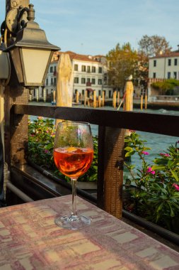 Şarap kadehinde Aperol Spritz kokteyli. Masanın üstünde, Venedik kanalının arka planında.