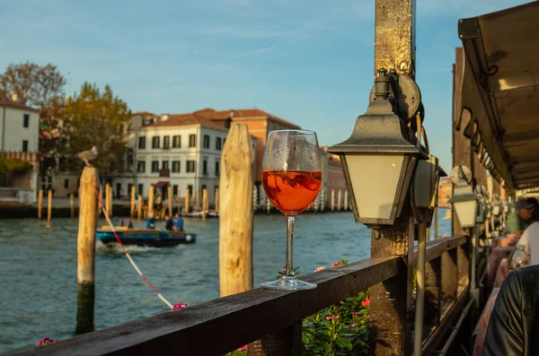  Venedik arka planında şarap bardağında Aperol Spritz kokteyli. Evlerin ön cephelerinde ve kanal suyunda.