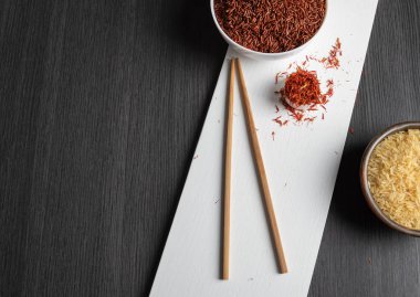 Kahverengi pirinç ve pirinçli pirinçli pirinçli pirinçli pirinçler ve siyah ahşap bir masada safran.