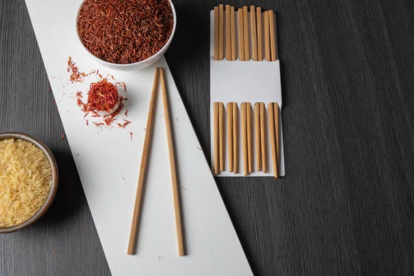 Kahverengi pirinç ve pirinçli pirinçli pirinçli pirinçli pirinçler ve siyah ahşap bir masada safran.