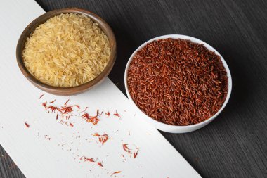 Beyaz tahta ve siyah zemin üzerinde Basmati pilavı ve kahverengi pirinç manzarası.