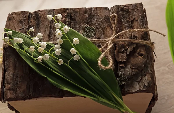 box for decor made of wooden bark with lily of the valley flowers. Silver lily of the valley