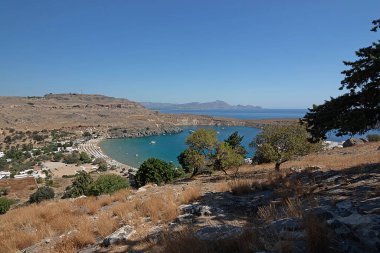Deniz yüzeyinin ve sahilin panoramik görüntüsü. Kayalık bir uçurumun kenarında. Denizcilik geçmişi Yunanistan, Rodos