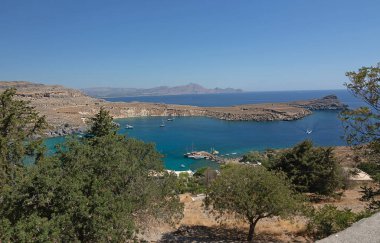 Deniz yüzeyinin ve sahilin panoramik görüntüsü. Ağaçların yeşilliğine bak. Denizcilik geçmişi Yunanistan, Rodos