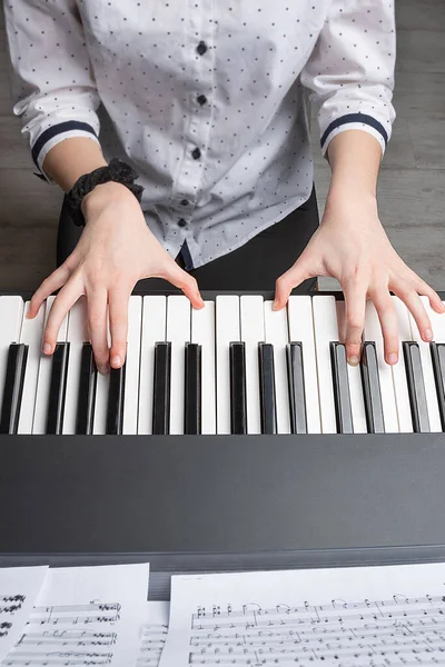 girl playing the piano, top view. Hands of a girl on the keys of a synthesizer. Stay at home