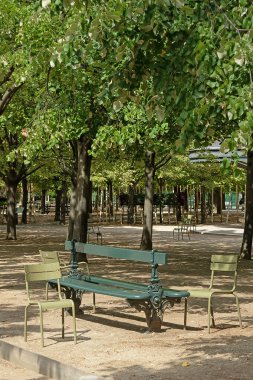 Parktaki bankta ve metal sandalyelerde. Öğleden sonra terk edilmiş park.