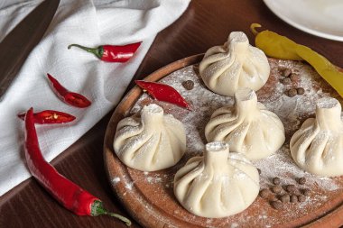 Mutfak tahtasında çiğ khinkali pişirdim. Bitki ve biberle. Geleneksel Gürcistan yemeğinin üst görünümü