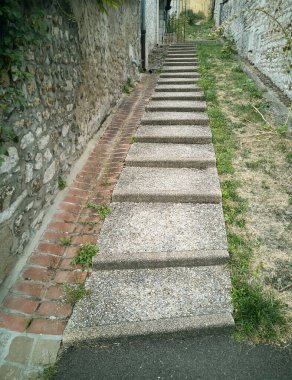 Bahçenin önündeki patikada taş duvarların arasındaki girişte.