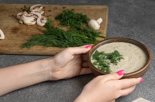 female hands hold a plate with vegetable cream soup. Detox diet. Diet mushroom soup with dill