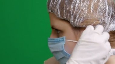 Yakın plan. Kız koruyucu bir tıbbi maske ve sağlık üniforması takıyor. Salgın virüsünün paniğinde. Kapalı. Hemşire hanım. Doktor bey. Koronavirüs salgını tehlikesi 2019-ncov. Karantina, korkular. Kromakey.