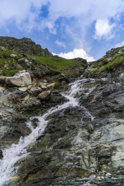 Şelale ve kayalarla kaplı dağ manzarası