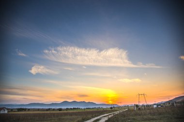 Bulutlar ve güneş ışınlarıyla tarlanın üzerinde gün batımı
