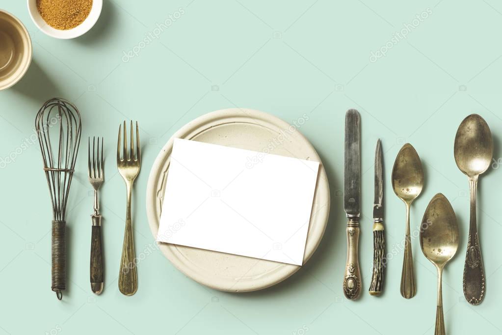 menu place setting with empty card and golden fork over blue bac