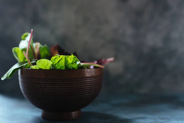 Varieties of lettuce, fresh holas in a wooden bowl over rustic t — Stock Photo, Image