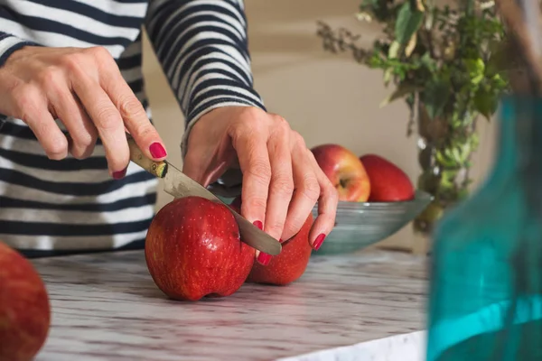 Kobieta cięcie jabłka na stole — Zdjęcie stockowe