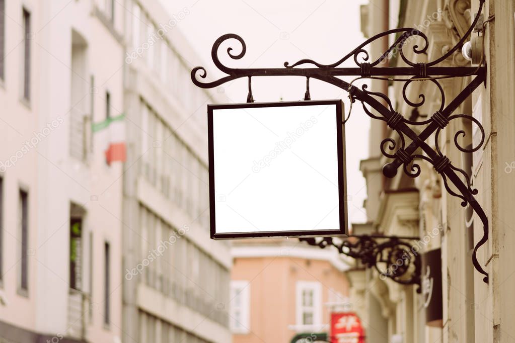 Blank square signboard, hanging from wrought iron bracket