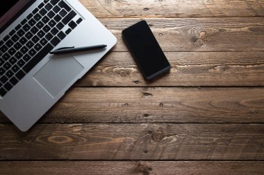 Ahşap masa üzerinde açık dizüstü bilgisayar ve cep, üstten görünüm