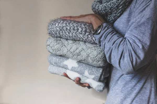 Mujer sosteniendo una pila de ropa de lana de invierno — Foto de Stock