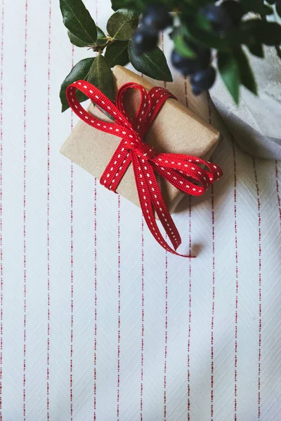 Pudełka na prezenty, owinięty w papier z recyklingu i czerwona kokarda na białych tabl — Zdjęcie stockowe