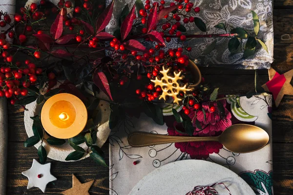 Vela encendida en la mesa de Navidad, rodeada de decoración festiva — Foto de Stock