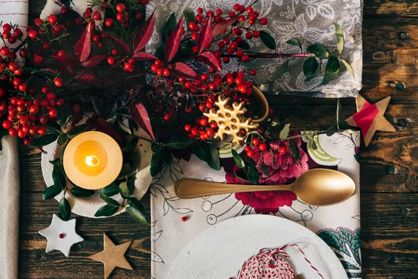 Candle lit on the Christmas table, surrounded by festive decorat — Stock Photo, Image