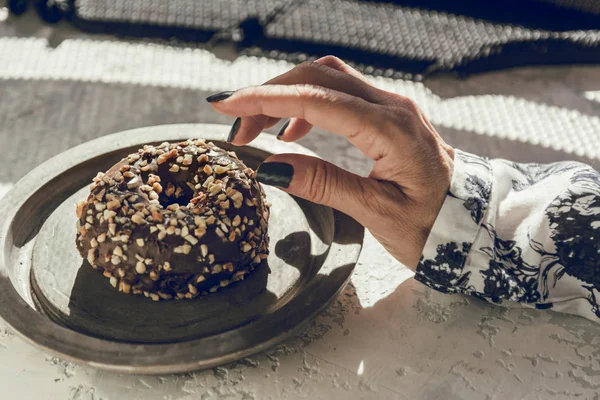 Kvinnas hand plocka en chocolate donut — Stockfoto