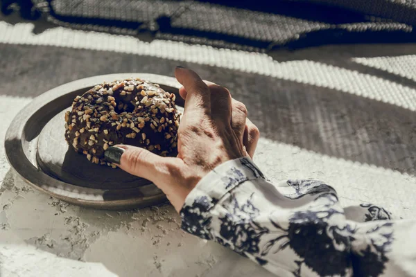 La mano de la mujer recogiendo un donut de chocolate —  Fotos de Stock