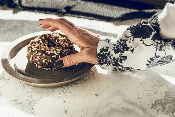 Mano della donna raccogliendo una ciambella al cioccolato — Foto Stock