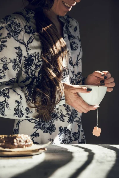 modern woman with tea cup, smile next to the sun from the window