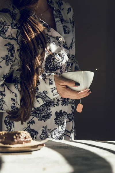お茶カップでモダンな女性が窓から太陽の横に笑顔します。 — ストック写真