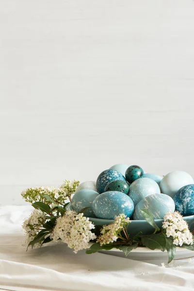 Natürlich gefärbte Ostereier, umgeben von weißen Blüten. — Stockfoto