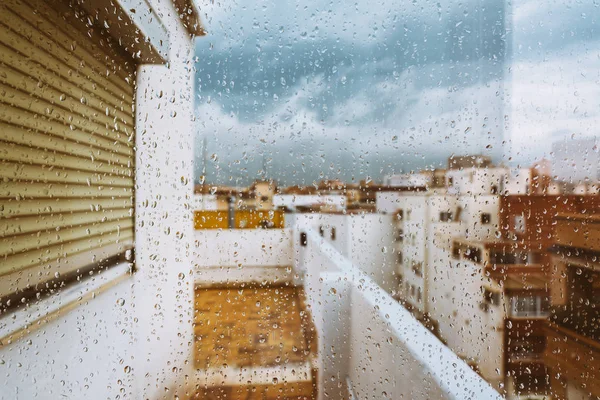 Window with raindrops on it, overlooking the terrace. stormy sky