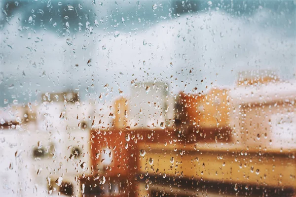 Window with raindrops on it, overlooking the terrace. stormy sky