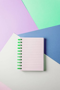 Renkli pastel arka planda yeşil spiral ve boş sayfalı bir defter aç. Eğitim kavramı, fikirler, planlar. Mesaj için yer. Minimalizm, düz uzanma.