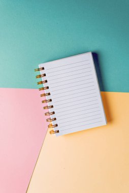 Renkli pastel arka planda altın spiral ve boş sayfalı bir defter aç. Eğitim kavramı, fikirler, planlar. Mesaj için yer. Minimalizm, düz uzanma.