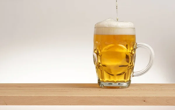 Becher leichtes Bier auf einem Holzbrett. — Stockfoto