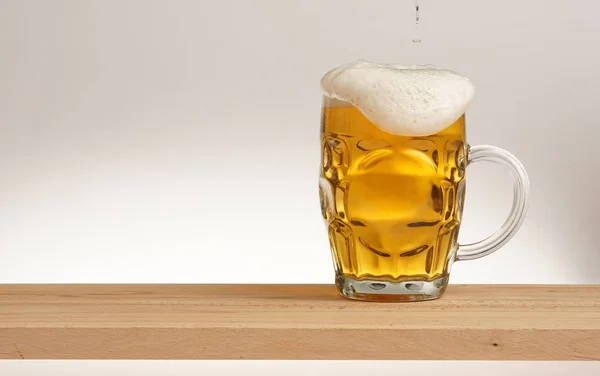 Becher leichtes Bier auf einem Holzbrett. — Stockfoto