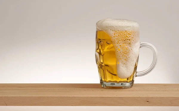 Copo de cerveja leve em uma tábua de madeira . — Fotografia de Stock