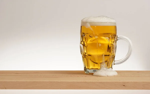 Taza de cerveza ligera en una tabla de madera . — Foto de Stock