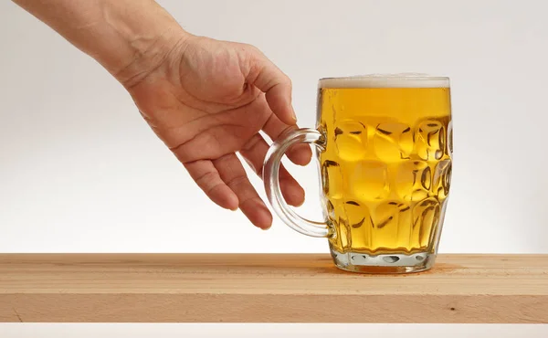 Hand ein Glas leichtes Bier vom Holzbrett nehmen. — Stockfoto