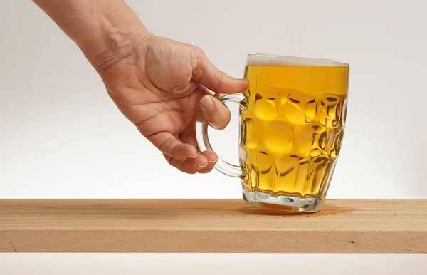 Hand ein Glas leichtes Bier vom Holzbrett nehmen. — Stockfoto