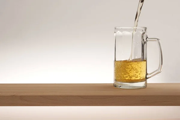 Taza de cerveza ligera en una tabla de madera . —  Fotos de Stock