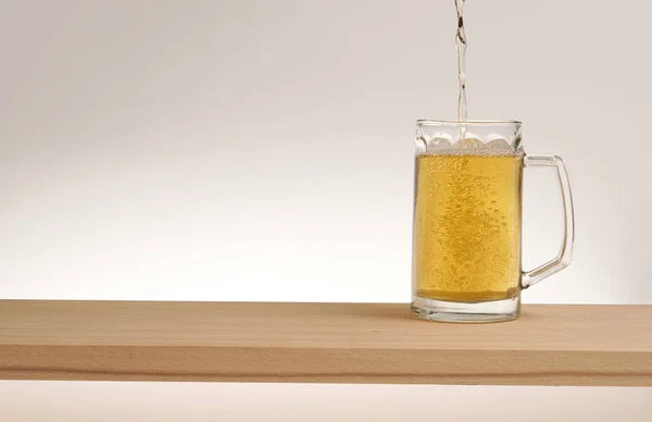 Taza de cerveza ligera en una tabla de madera . —  Fotos de Stock