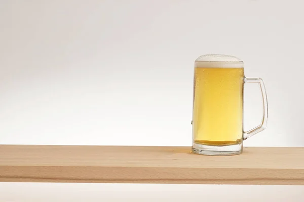 Кружка светлого пива на деревянной доске . — стоковое фото