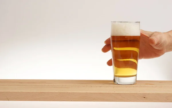 Hand take glass of light beer from wooden board. — Stock Photo, Image