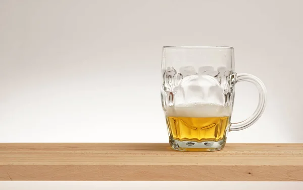 Becher leichtes Bier auf einem Holzbrett. — Stockfoto