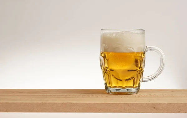 Ποτήρι ελαφριά μπίρα σε ένα ξύλινο ταμπλό με. — Φωτογραφία Αρχείου