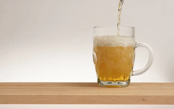 Copo de cerveja leve em uma tábua de madeira . — Fotografia de Stock