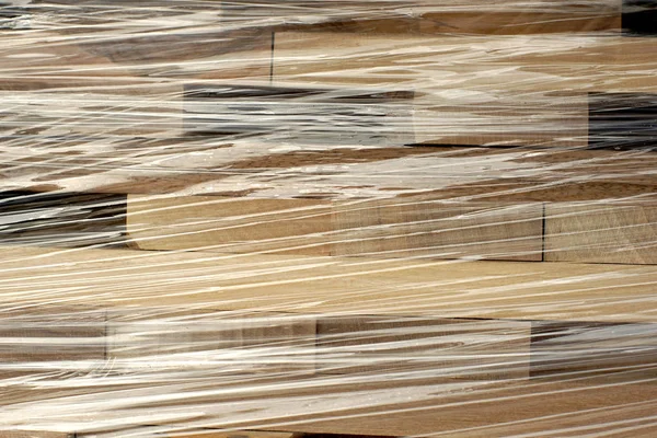 Wooden planks stacked in rows wrapped in plastic foil — Stock Photo, Image